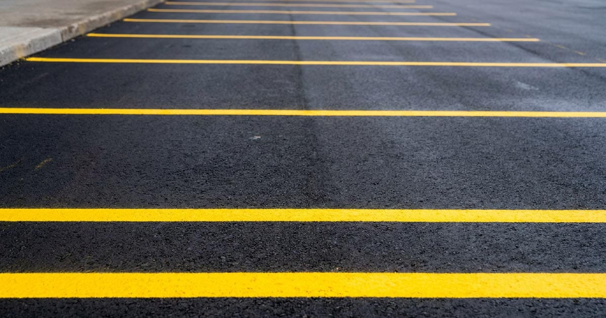 Freshly painted parking lot stall lines on dark asphalt